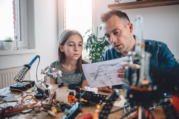 Père et fille regardant des schémas électroniques