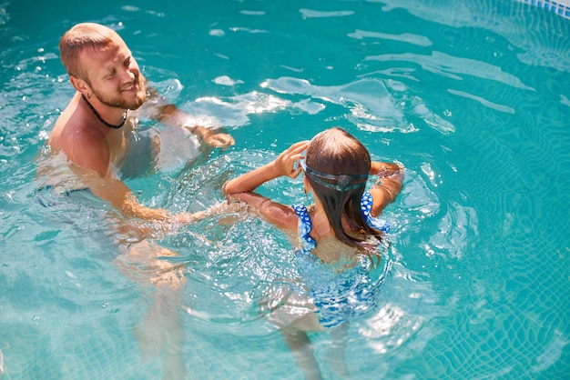 Père et fille s'amusent dans la piscine à la maison