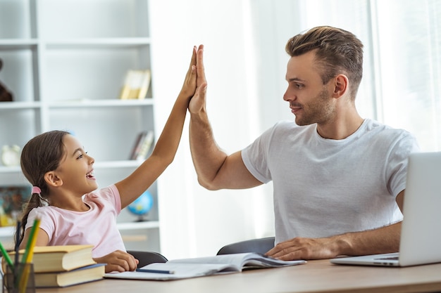 Le père et une fille s'asseyant à la table et faisant des gestes