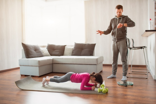 Le père et la fille s'entraînent à la maison. Séance d'entraînement dans l'appartement.