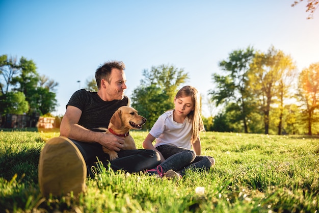 Père et fille se détendre au parc avec chien