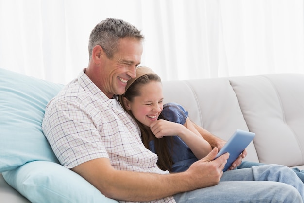 Père et fille se détendre sur le canapé en utilisant un ordinateur portable