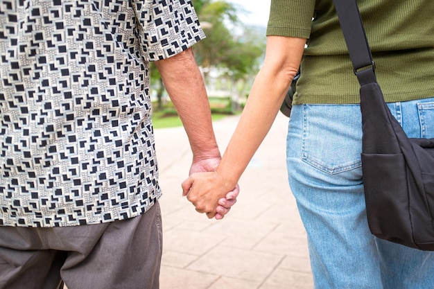 Père et fille se tenant la main en marchant dans le parc