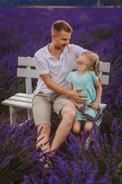 Père et fille sont assis sur un banc dans un champ de lavande