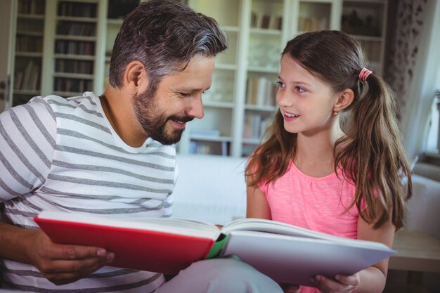 Père et fille souriante regardant album photo dans le salon