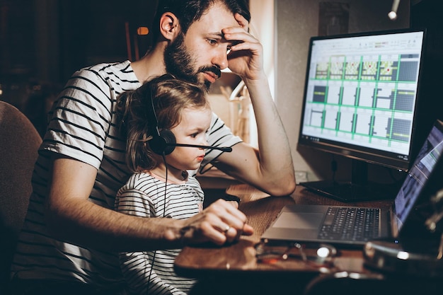 Père et fille travaillent sur un ordinateur portable homme d'affaires travaillant à domicile et regardant l'enfant Un jeune homme travaille sur un ordinateur Lancer le concept Freelancer Famille en quarantaine