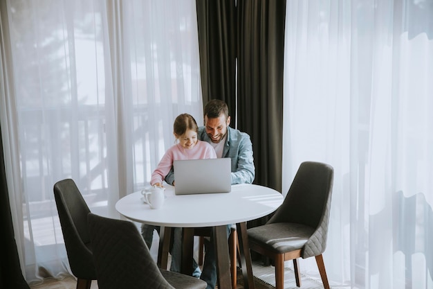 Père et fille utilisant un ordinateur portable ensemble dans la chambre