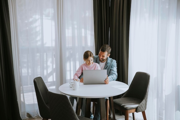 Père et fille utilisant un ordinateur portable ensemble dans la chambre