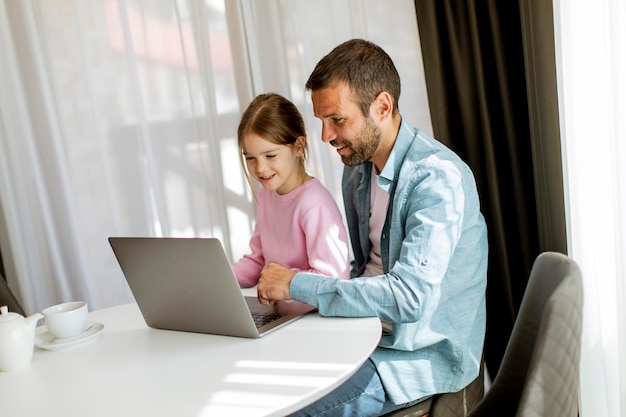 Père et fille utilisant un ordinateur portable ensemble dans la chambre