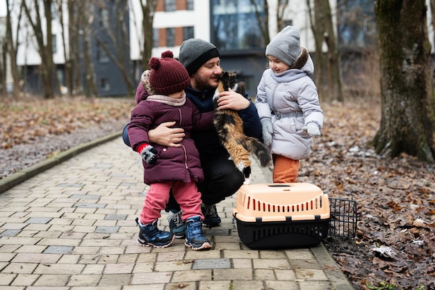 Père et filles avec chat en cage en plastique pour animaux de compagnie de voyage en plein air au parc