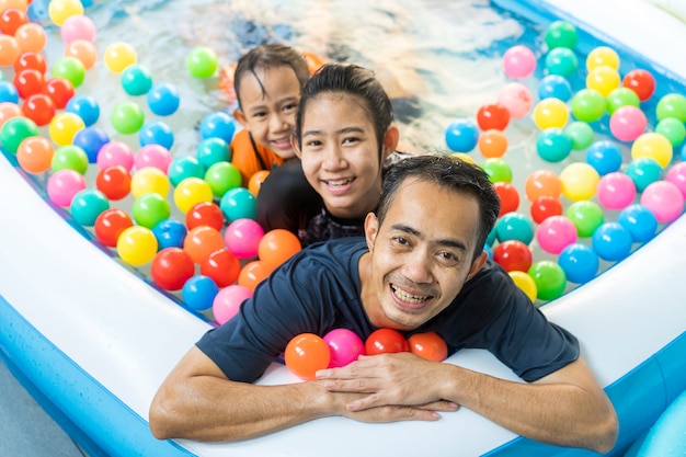 Père et filles jouant dans une piscine