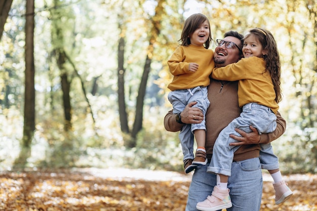 Père avec filles s'amusant dans un parc automnal