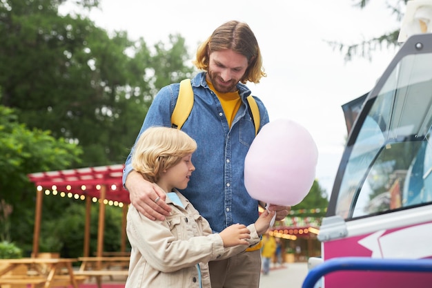 Père et fils achetant de la barbe à papa au festival