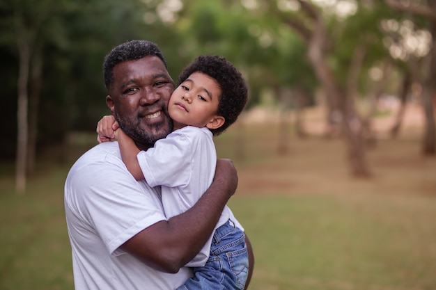 Père et fils afro se tenant dans le parc. Fête des pères.