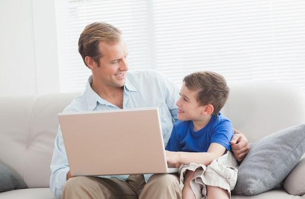 Père et fils à l&#39;aide d&#39;ordinateur portable sur le canapé