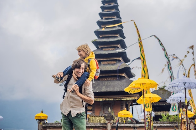 Père et fils à l'arrière-plan du temple hindou pura ulun danu bratan bali entouré de fleurs sur