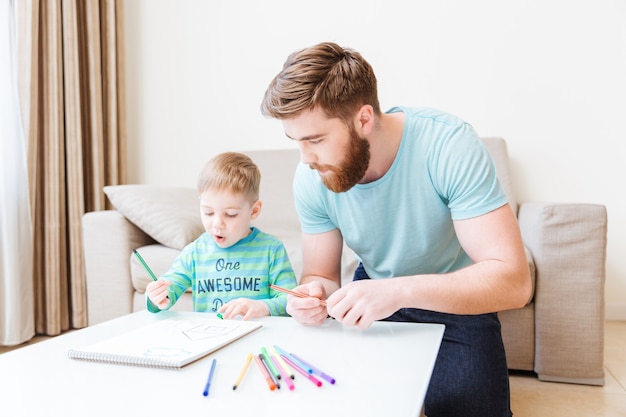 Père et fils assis et dessinant dans le salon à la maison