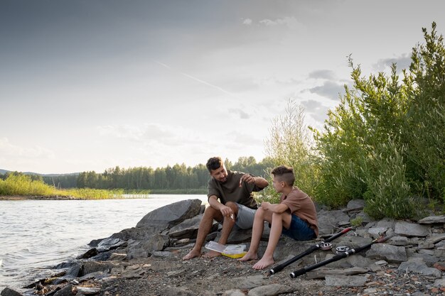 Père et fils assis devant le lac en pêchant