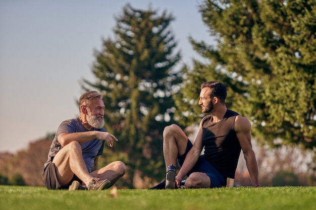 Le père et le fils assis sur l'herbe et parlant