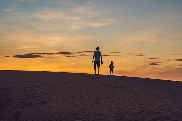 Père et fils au désert rouge à l'aube voyageant avec des enfants