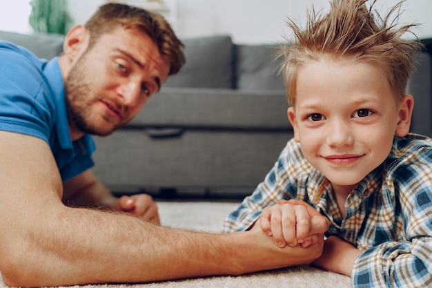 Père et fils bras de fer sur un tapis à la maison clsoe up