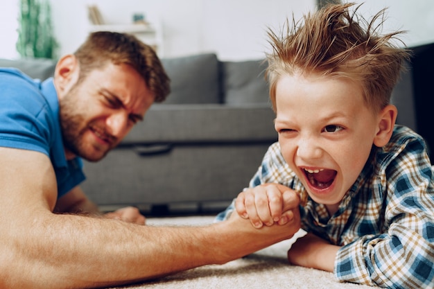 Père et fils bras de fer sur un tapis à la maison clsoe up