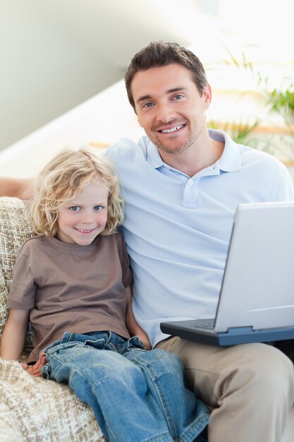 Père et fils sur le canapé avec ordinateur portable