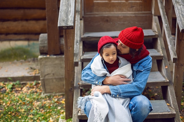 Père et fils en chapeaux rouges et écharpes tricotées sont assis