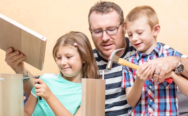 Le père et les fils construisent les meubles à la maison