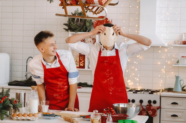 Père et fils dans la cuisine de Noël préparent la pâte pour faire des biscuits.