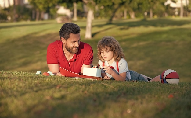 Père et fils dessinant en plein air bonne fête des pères famille heureuse papa et enfant garçon se détendre sur l'herbe