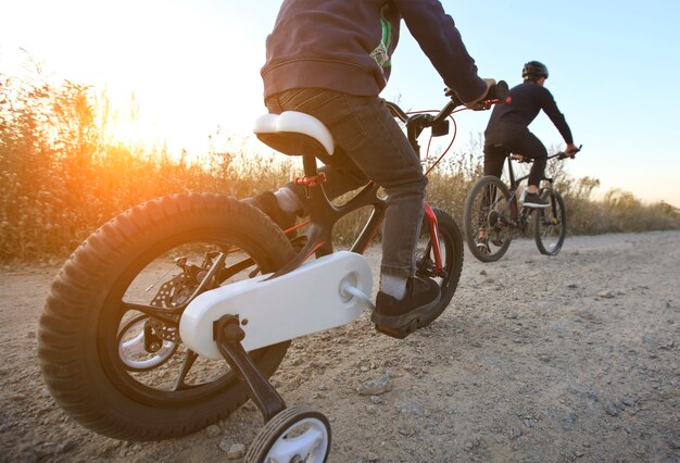 Père et fils ensemble font du vélo à travers le chemin sur le terrain