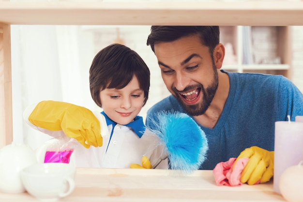 Père et fils essuyent les surfaces de meubles de la poussière