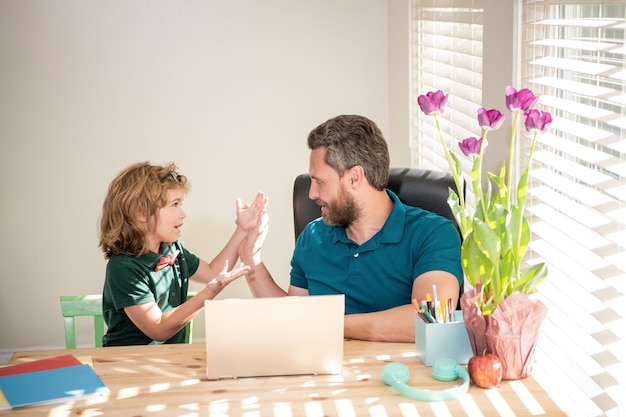 Père et fils étonnés à l'école travaillant en ligne sur un ordinateur portable