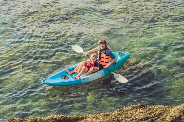 Père et fils faisant du kayak dans l'océan tropical.