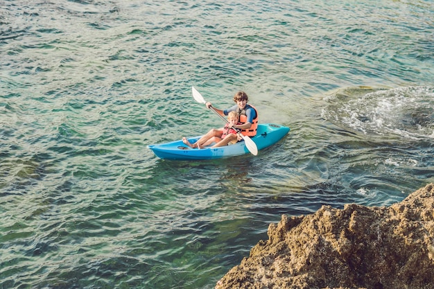 Père et fils faisant du kayak dans l'océan tropical.