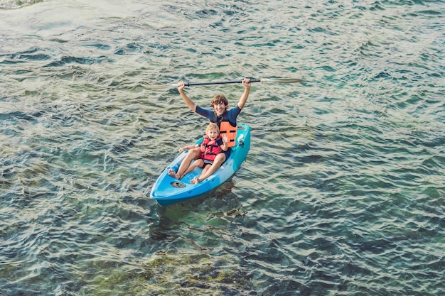 Père et fils faisant du kayak dans l'océan tropical.