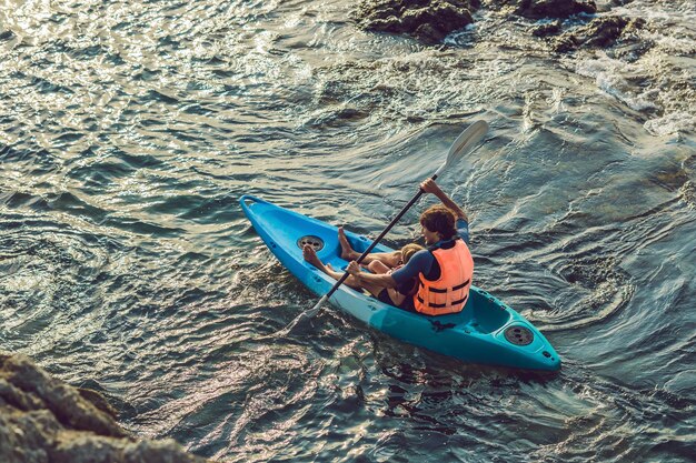 Père et fils faisant du kayak dans l'océan tropical.