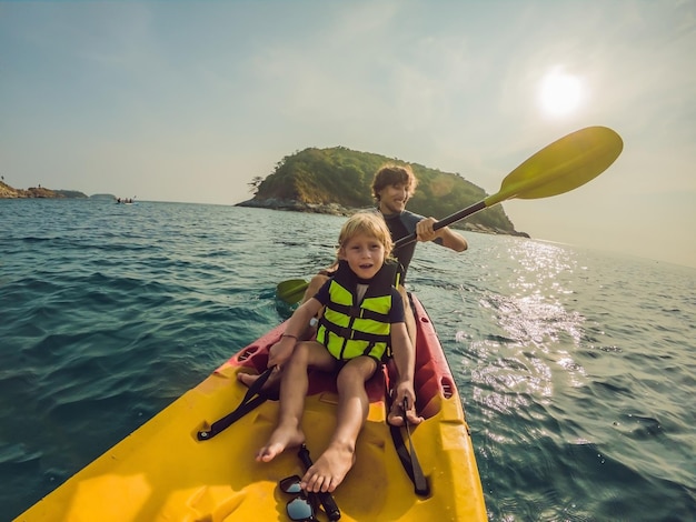 Père et fils faisant du kayak dans l'océan tropical.