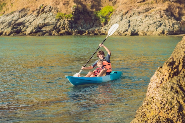 Père et fils faisant du kayak dans l'océan tropical.