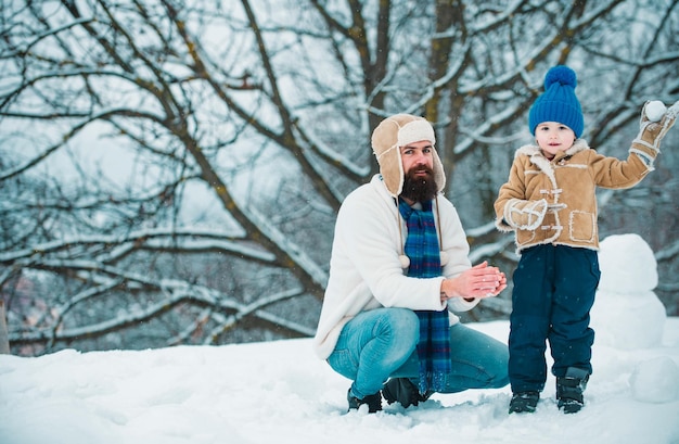 Un père et un fils heureux jouent en hiver, à Noël, à la fête des pères, un enfant heureux jouant avec une boule de neige.