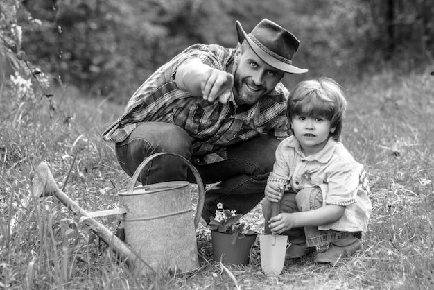 Père et fils jardinage petit fils aidant son père à planter l'arbre tout en travaillant ensemble en t