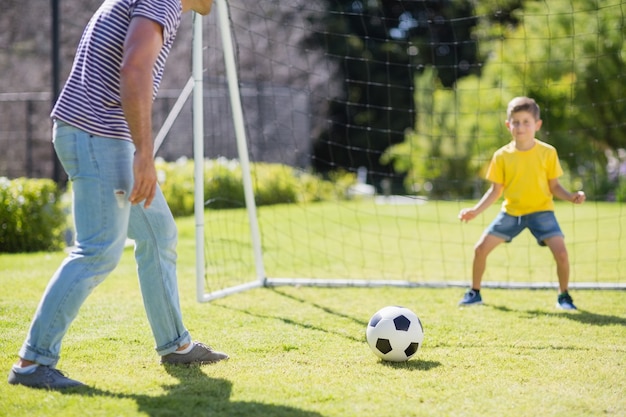 Père et fils jouant au football dans le parc