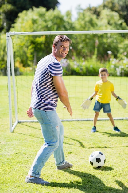 Père et fils jouant au football dans le parc