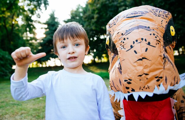 Père et fils jouant au parc, avec un costume de dinosaure, s'amusant avec la famille en plein air