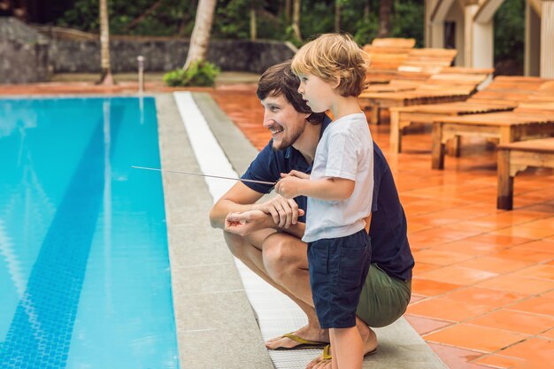 Père et fils jouant avec un bateau télécommandé dans la piscine