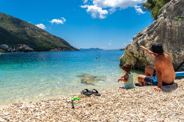 Père et fils jouant sur la plage de Paralia Mikros Gialos à Lefkada jetant des pierres en Grèce