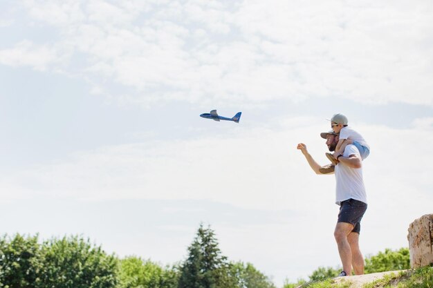 Père et fils jouent dans le parc avec un jouet d'avion