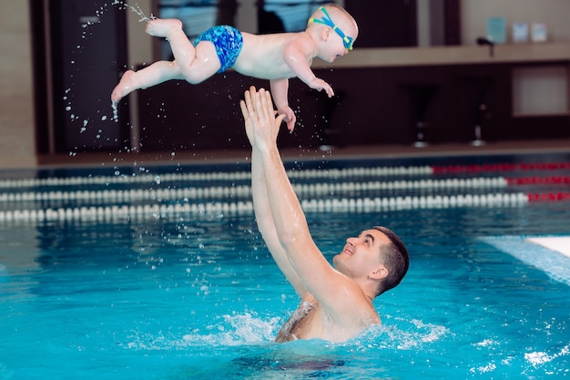 Père et fils jouent dans la piscine. le père jette le fils.