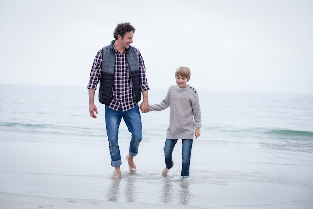 Père et fils marchant dans les eaux peu profondes au bord de la mer